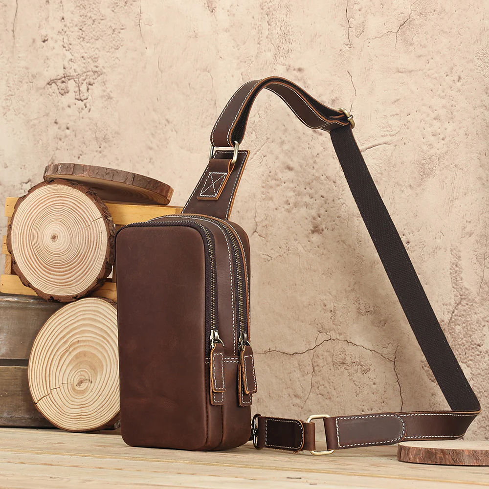 The Blaze leather sling bag styled against a rustic wall